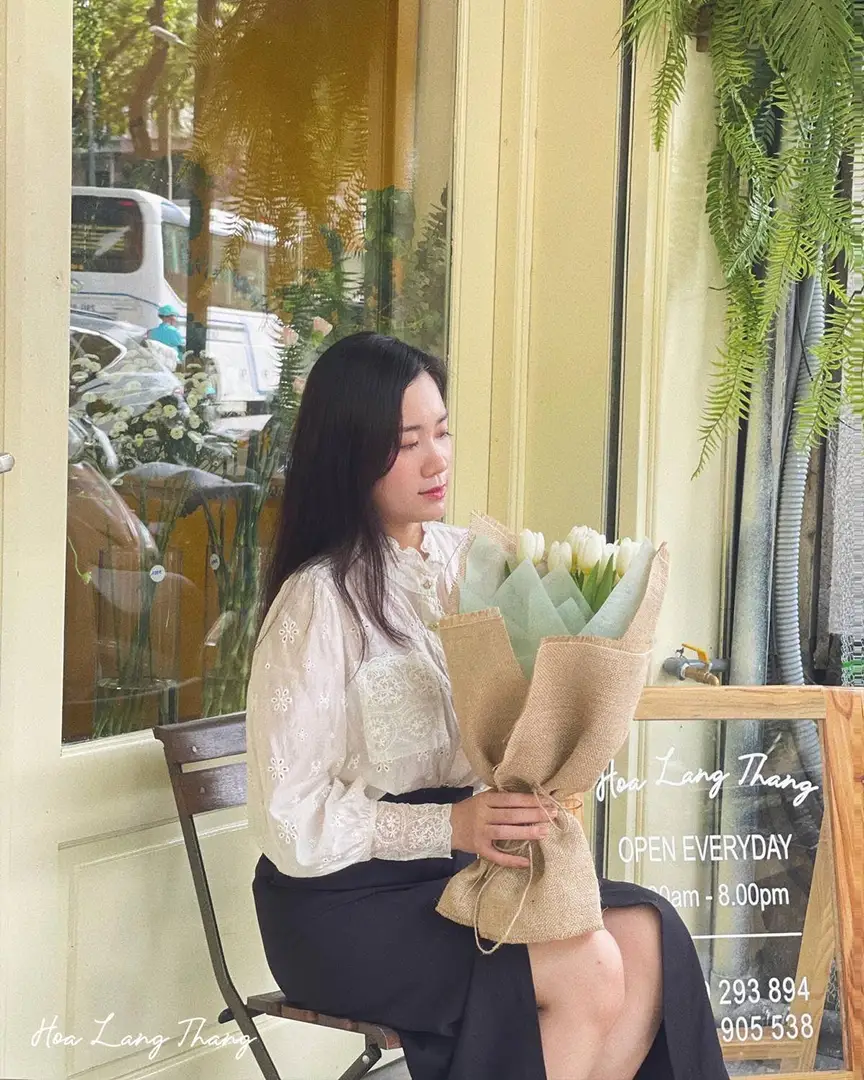 Cô gái cầm bó hoa sen trắng, chụp tại cửa hàng Hoa Lang Thang ở Hà Nội