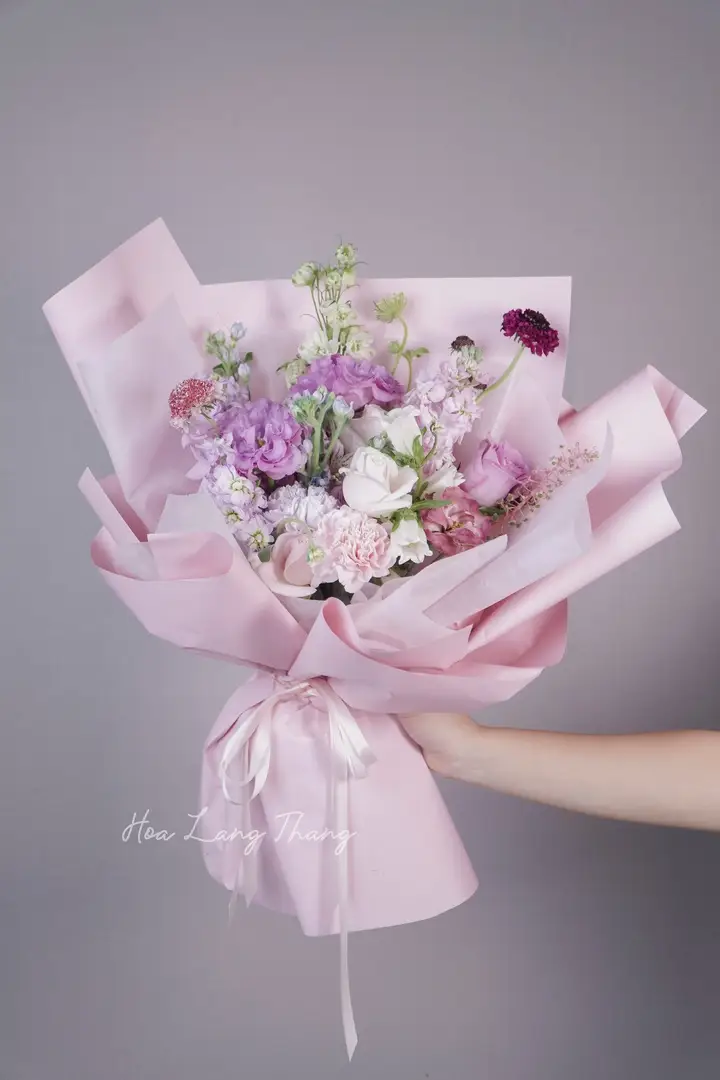 Bó hoa gồm nhiều loại hoa pastel trong giấy hồng, kiểu cắm đẹp mắt