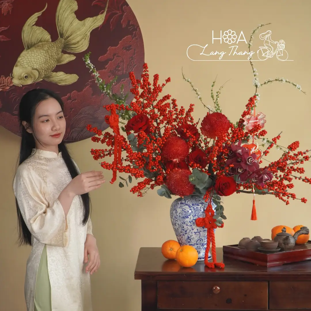 Bình hoa tươi với màu đỏ nổi bật, chứa hoa hồng, cúc và cam tú cầu, kiểu cắm nghệ thuật